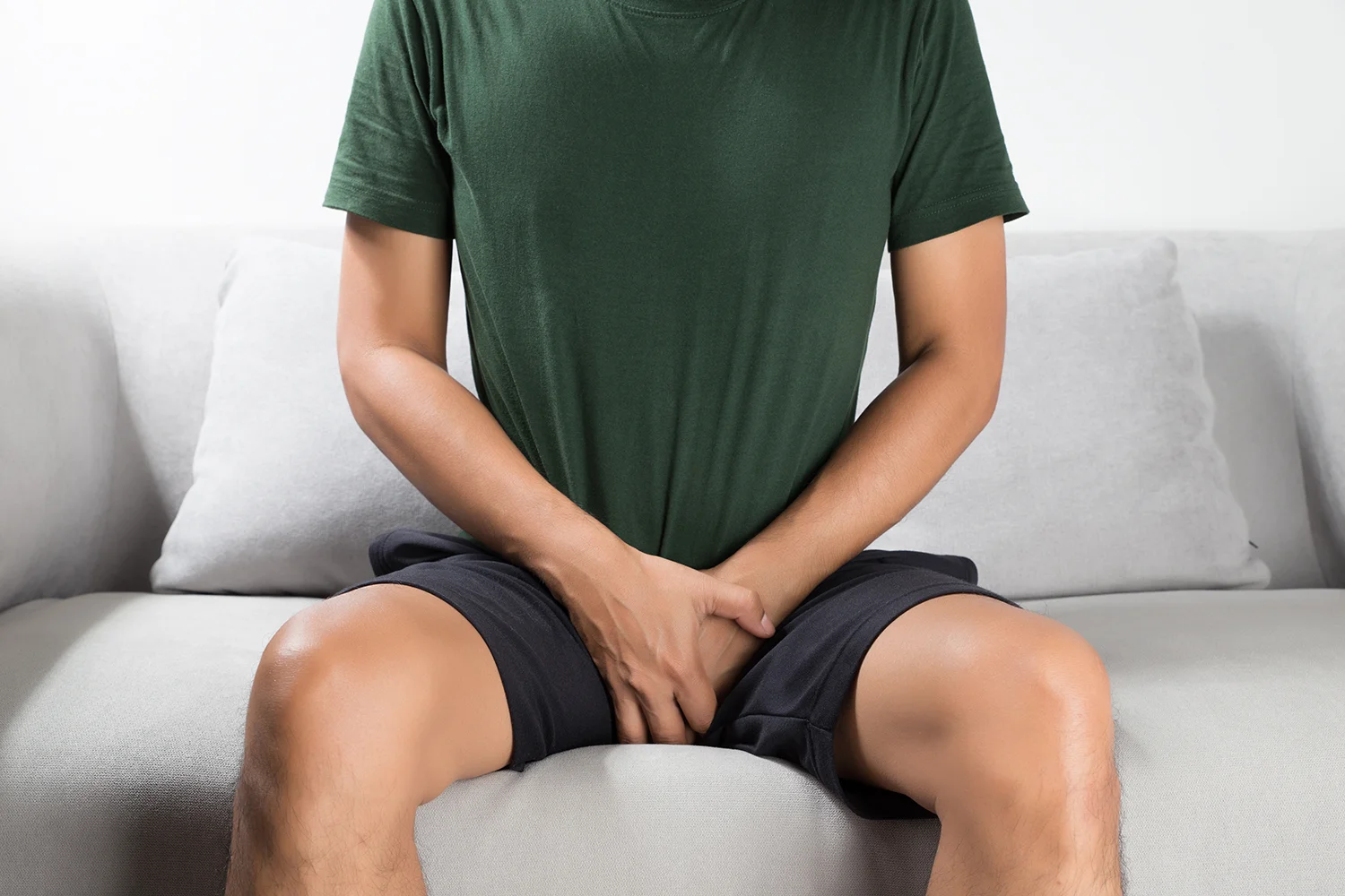 man on sofa holding crotch
